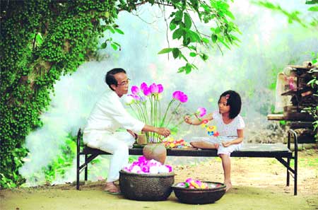 Picture perfect: A little girl lends a hand as artist Than Van Huy arranges a vase of paper lotus flowers in the backyard of his house.